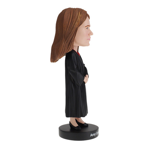 Right side view of Amy Coney Barrett Bobblehead figure is wearing judicial robes and long brown hair, standing on a base labeled "Amy Coney Barrett," conveying authority.