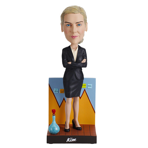 Better Call Saul Kim Wexler Bobblehead features a woman in a black suit with arms crossed, standing confidently in front of a chart backdrop. A blue bottle with a red cap is at her feet.