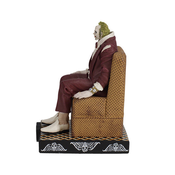 Left side view figurine of a character dressed in a maroon suit with green hair sits on a patterned chair. The base says "Beetlejuice," suggesting a playful tone.
