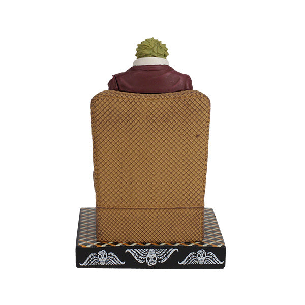 Back view of a figurine of a character dressed in a maroon suit with green hair sits on a patterned chair. The base says "Beetlejuice," suggesting a playful tone.