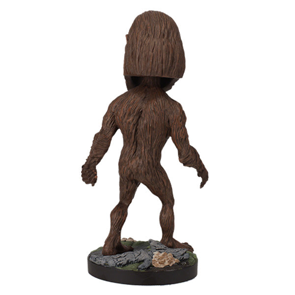 Back view of Bigfoot Bobblehead figure of Bigfoot with brown fur, large head, and detailed features standing on a green, rocky base labeled "BIGFOOT" in green letters.
