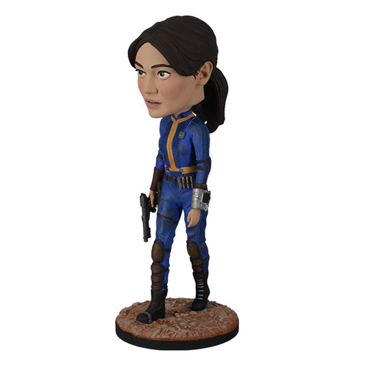 3/4 Left side view of action figure in blue and yellow jumpsuit holding a pistol on rugged base.