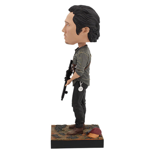 Left view Glenn bobblehead in camo shirt holding rifle on labeled base.