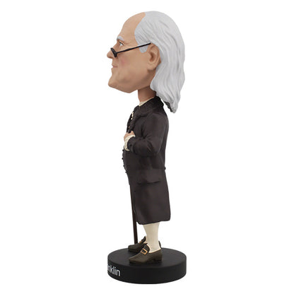 Left side view of Benjamin Franklin bobblehead featuring an elderly man with a bald head and long white hair, wearing glasses and colonial attire, stands on a base labeled "Ben Franklin."