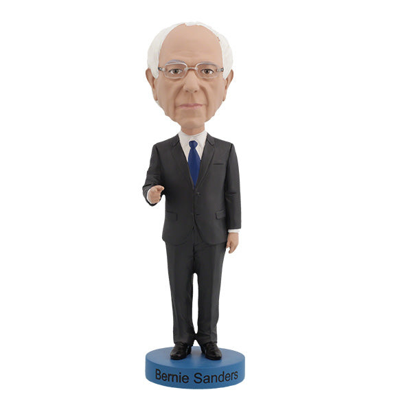 Bernie Sanders Bobblehead figurine of an elderly man with white hair and glasses, wearing a dark suit, standing on a base labeled "Bernie Sanders." The figure has a calm expression.