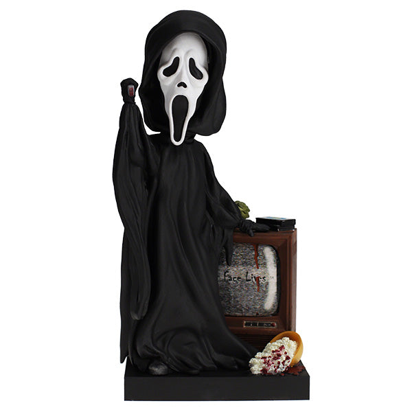 Ghost face in a  black robe and white mask with a television and bowl on a stand.