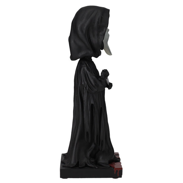 Statue of a hooded figure in black robes on a white background