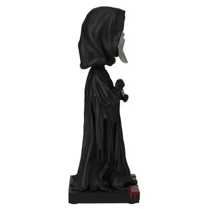 Statue of a hooded figure in black robes on a white background