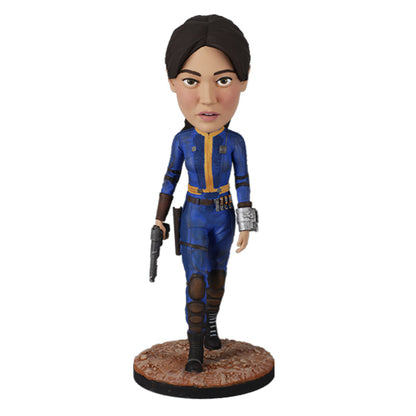 Action figure in blue and yellow jumpsuit holding a pistol on rugged base.