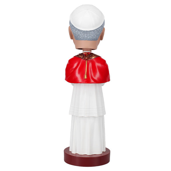 Backside view of a bobblehead of a smiling figure in papal attire with a red cape and ornate gold stole, posed against a plain background, labeled "Pope Leo XIV."